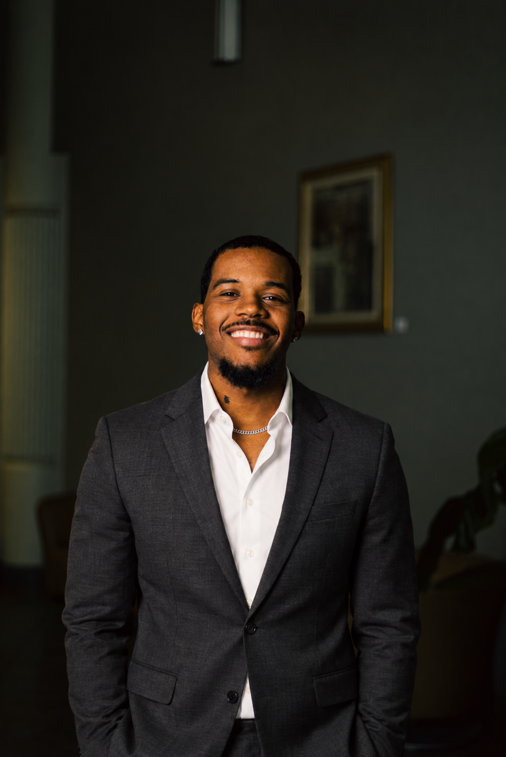 Carlos Henry smiling in a charcoal suit and white shirt